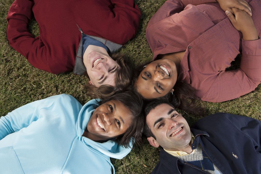 young adults laying on grass